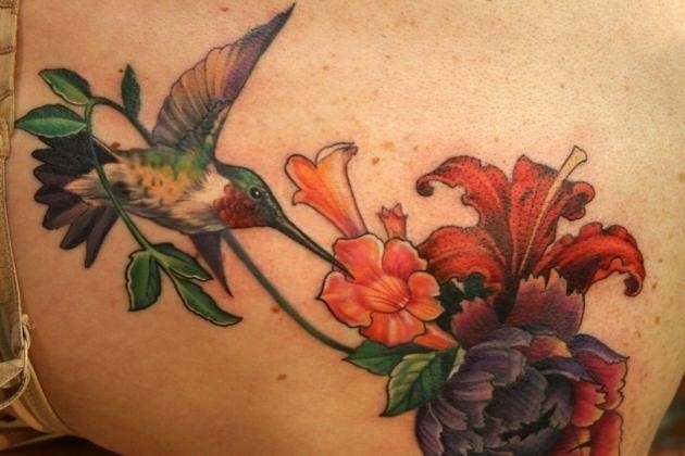 A beautiful tattoo of a hummingbird sipping nectar from a bouquet of flowers