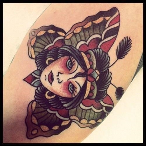 A beautiful woman surrounded by butterfly wings captivates the viewer in this old school tattoo by Karl Wiman