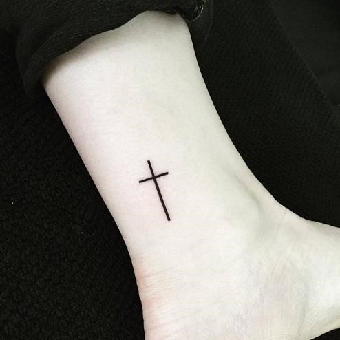 Black bold cross tattoo on right ankle