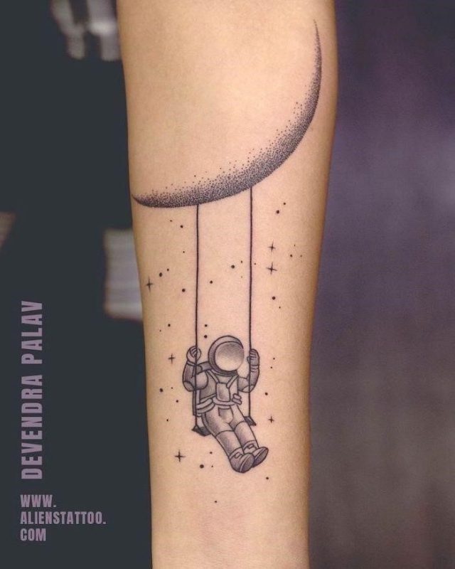 Astronaut swinging on a swing hanging from the moon small space tattoos forearm tattoo