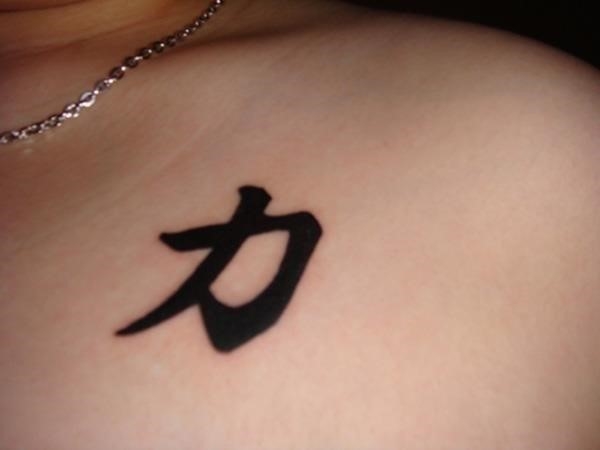 Black ink strength tattoo on left shoulder
