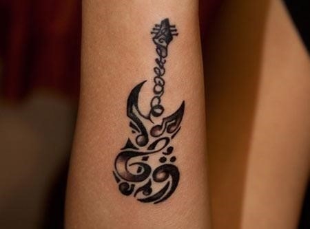Black tribal guitar tattoo on arm