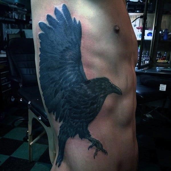 Bluish grey raven with large wings tattoo side ribs men