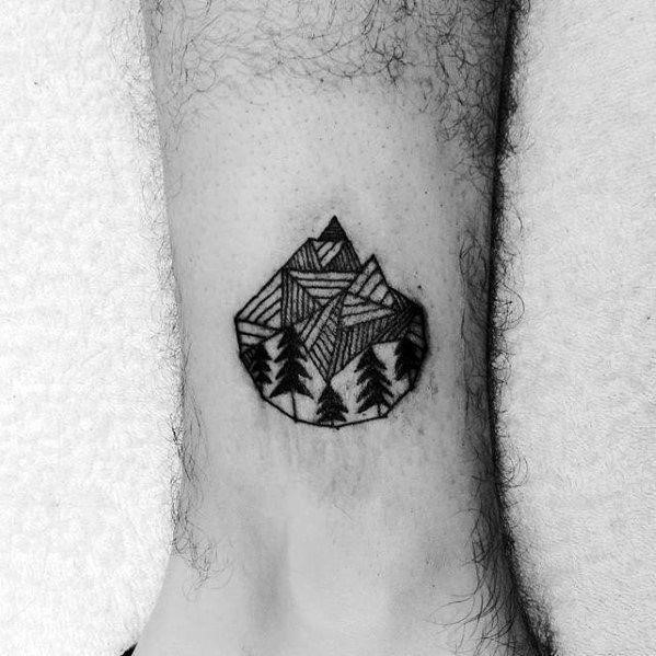 Guy with small nature landscape geometric lower leg tattoo design