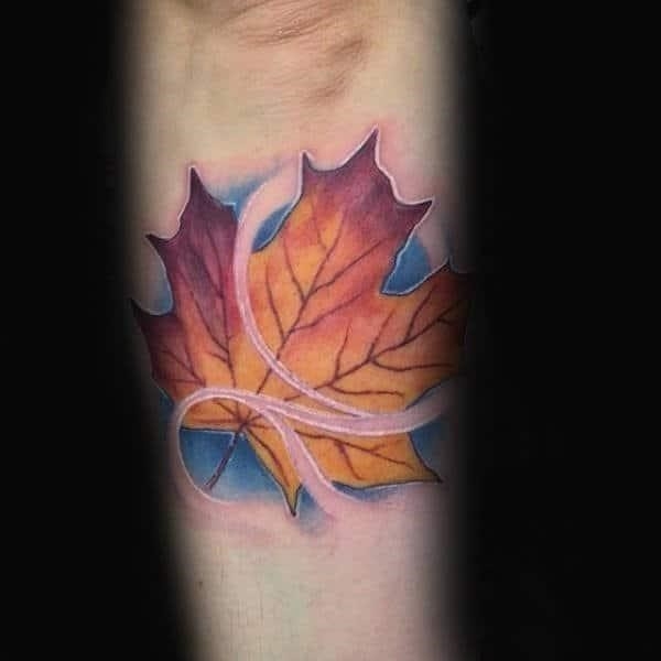 Guys small maple leaf blowing in the wind outer forearm tattoo