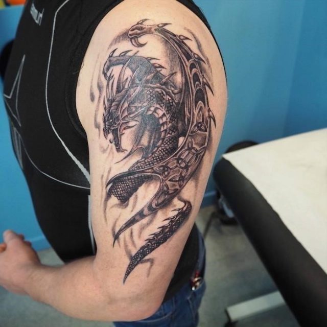 Large dragon shoulder tattoo man wearing a black top jeans forearm tattoos for men