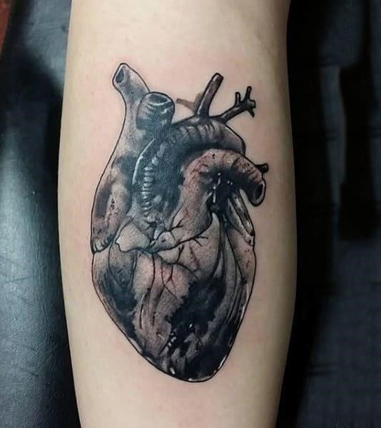 Male with heart tattoo in blck ink on forearm